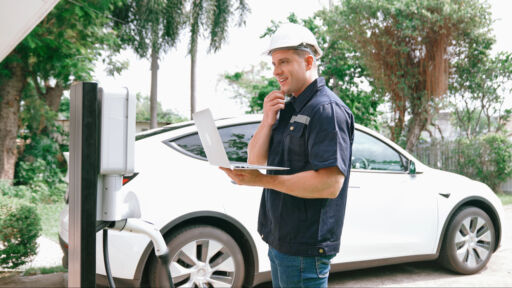 EV charging station repairs Qualified technician working on home EV charging station installation, making troubleshooting and configuration setup on charging system with laptop for EV at home. Synchronos